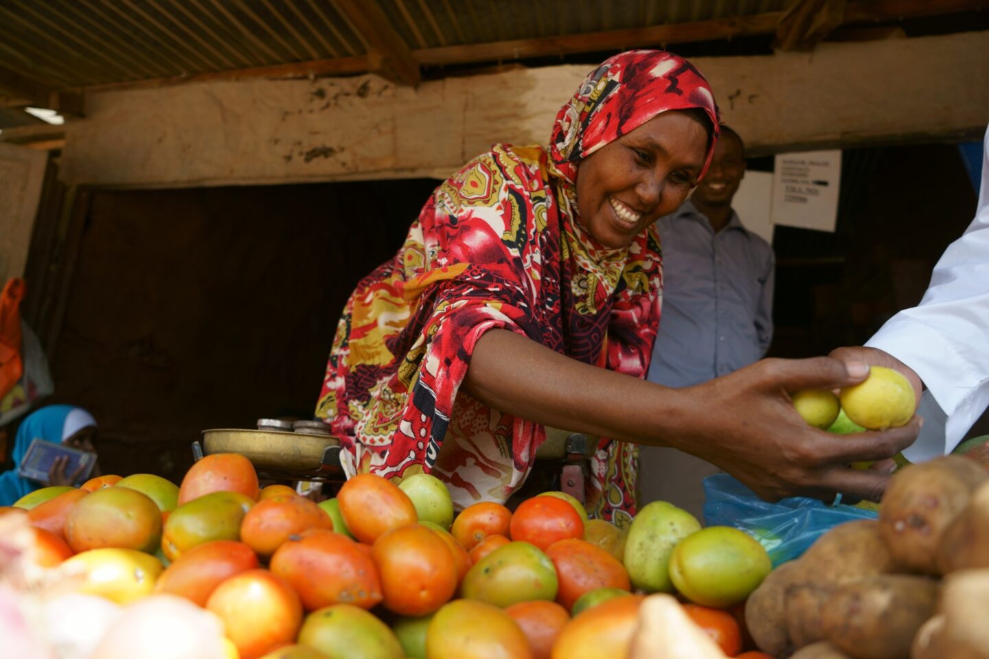 une femme réfugiée vend ses légumes sur le marché