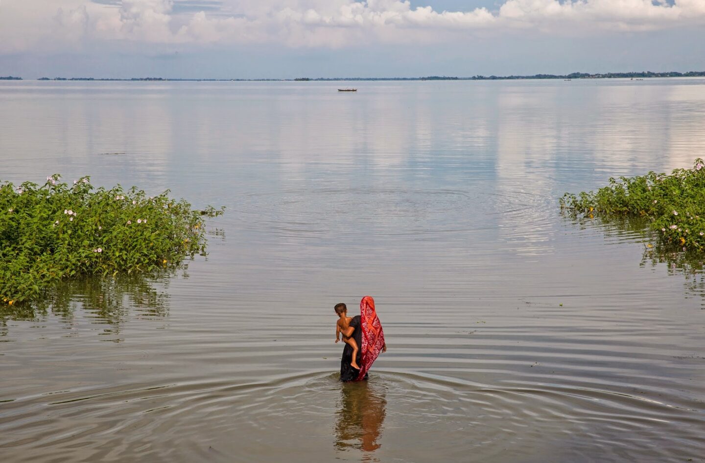 Une femme touchée par les inondations marche dans un lac en Asie